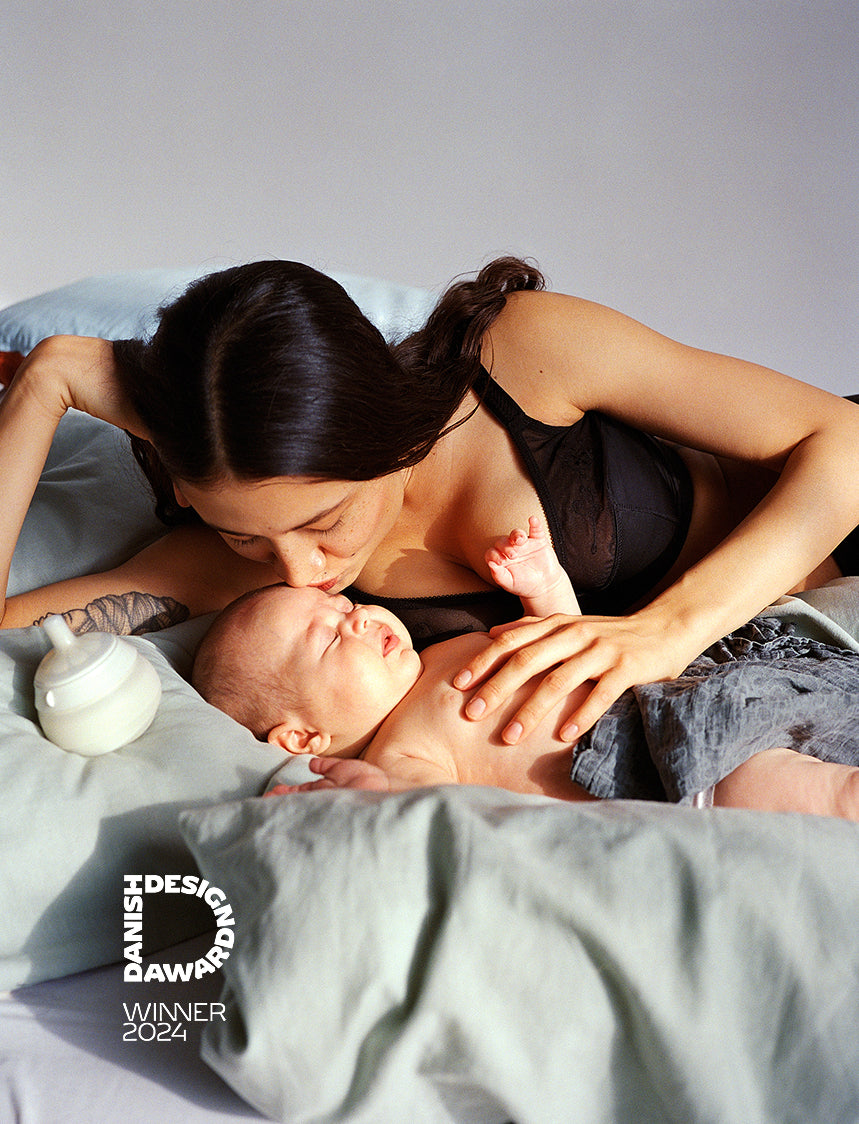 Mother kissing baby, nightnursing with the caramma support bottle that can be used laying down. Petra Kleis
