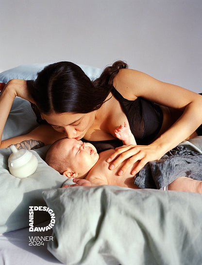 Mother kissing baby, nightnursing with the caramma support bottle that can be used laying down. Petra Kleis