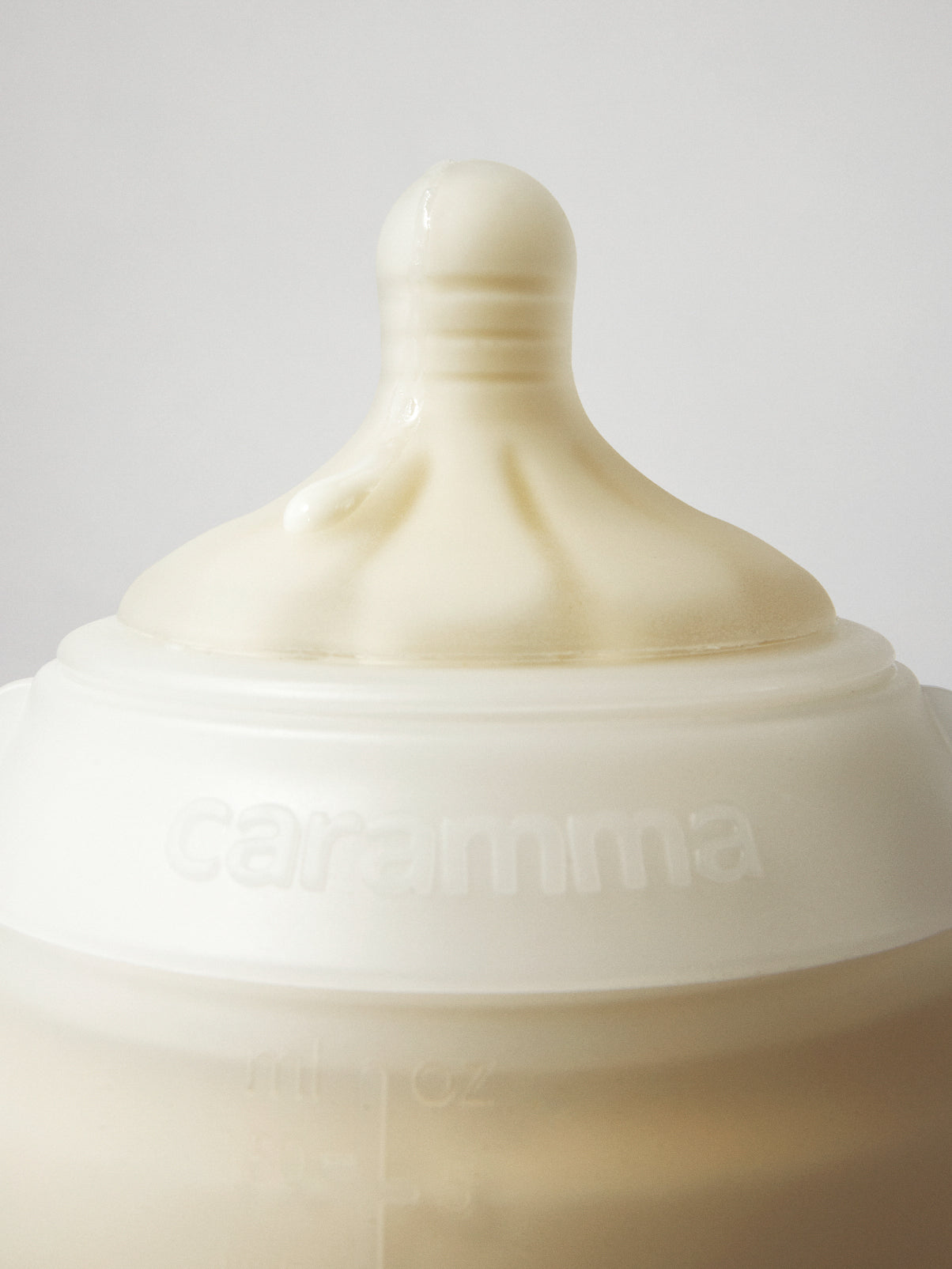 milk drop on caramma support baby bottle showing the logo, nipple, and soft silicone feel